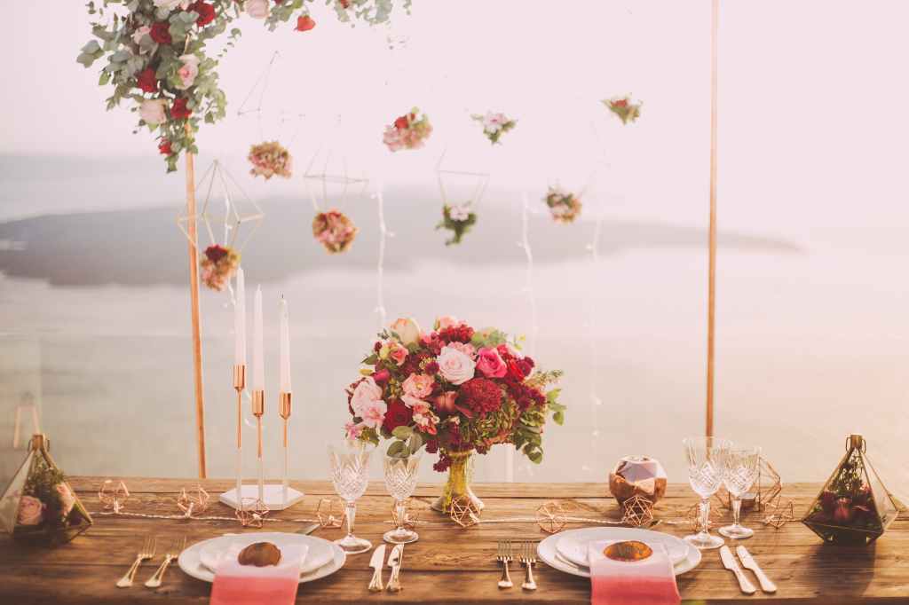 Delicate red and pink wedding flowers at the breakfast table with a backdrop of the sea. By Edward Ever www.pexe;s.com
