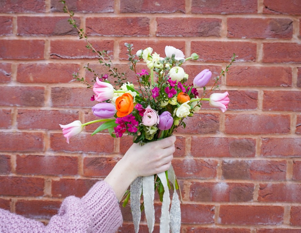 Hand held bouquet with tulips, ranunculus, and dianthus.