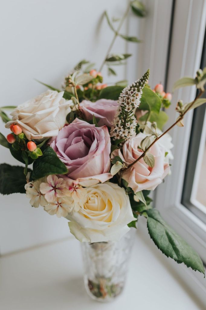 Bridesmaids bouquet on windowsill with pink and white roses, garden flowers, whimsical style.