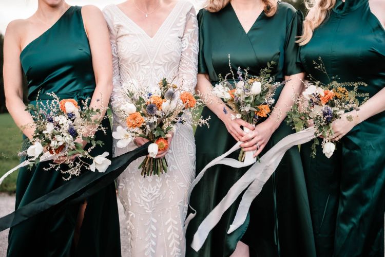 Close up of bouquets in dried and fresh british flowers with white and green ribbons