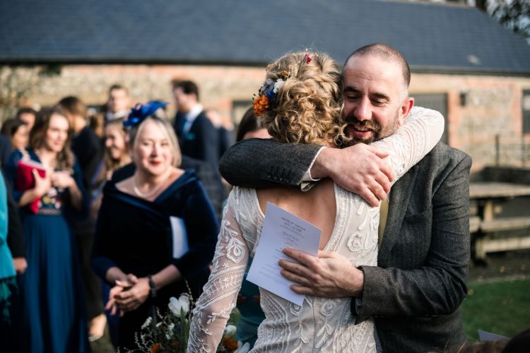 Bride hugging a guest with flowers in her hair