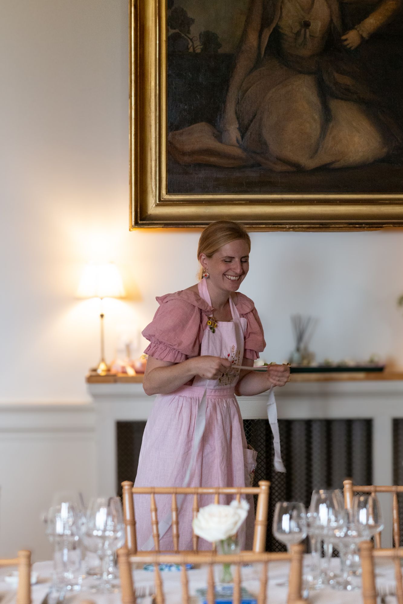Esme Ford of The Honey Seeker Floral Design tying ribbons around floral arrangements at wedding set up at North Cadbury Court in Somerset, picture by Orinta Fowler.