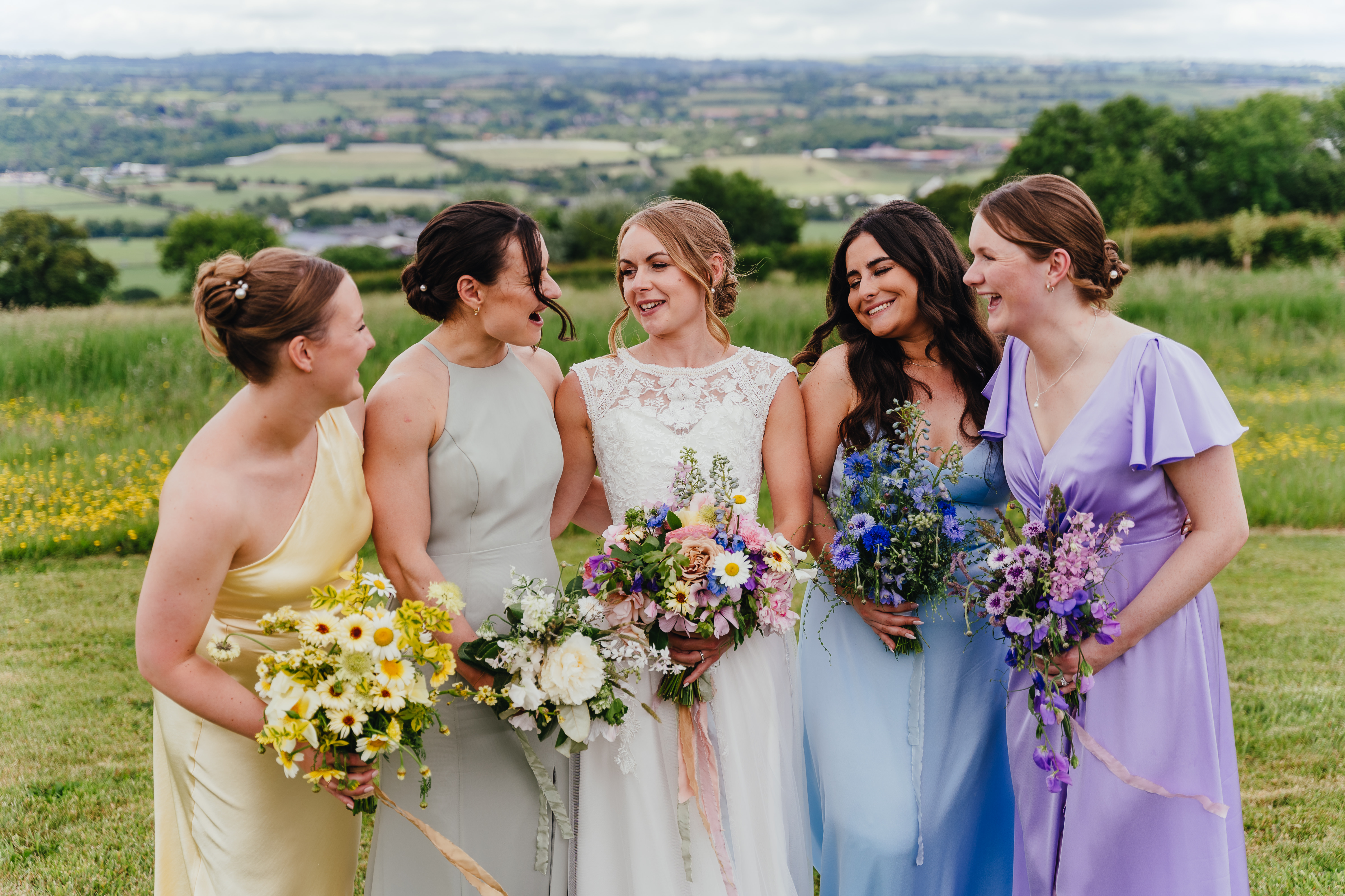 Bride with multicolour bouquet and bridesmaids with single colours each taken from the brides bouquet, at Pennard Hill Farm in Somerset, image by Freya Steele.